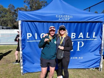 Two campers wearing medals in front of the Pickleball Camp marquee.