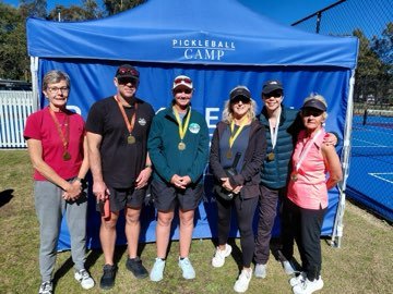 A group of medal-winning campers in front of the Pickleball Camp marquee.