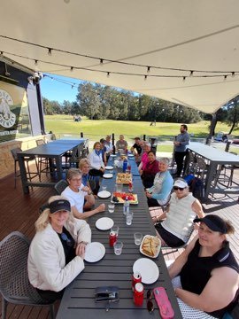 Campers seated together at a covered outdoor table.