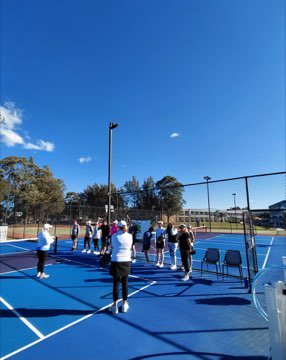 Campers gathered on the pickleball court during a coaching session.