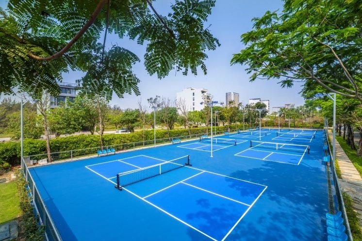 The Furama Resort's blue pickleball courts under tall tropical trees