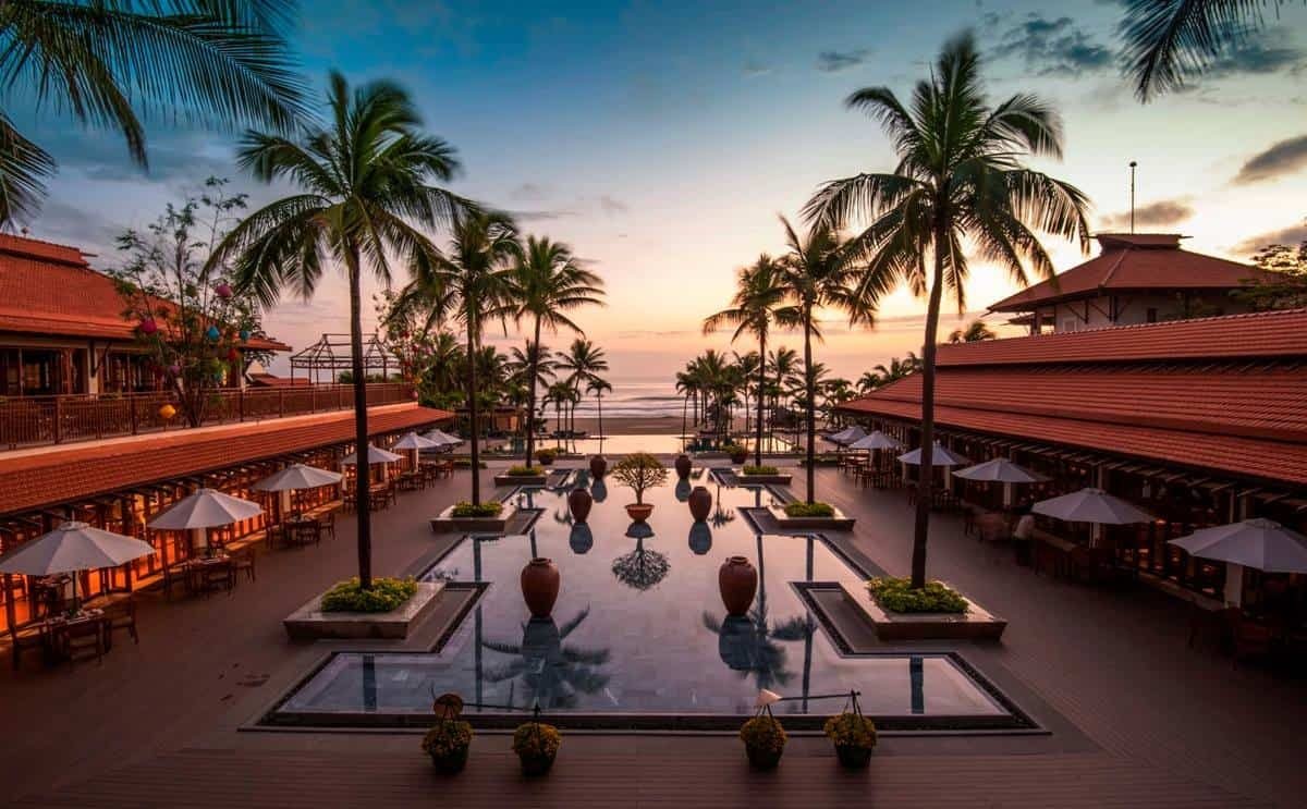 The palm-lined pool courtyard of the Furama Resort Da Nang at sunset