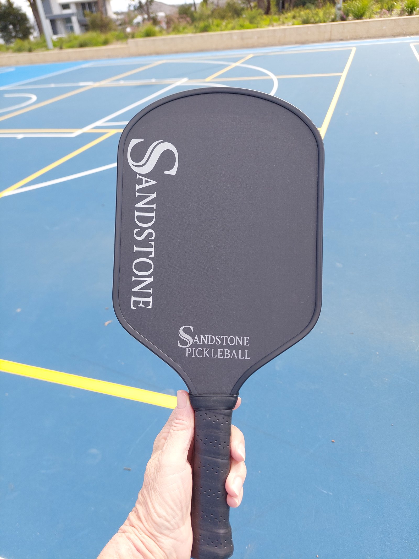 Sandstone Paddle held in hand on court